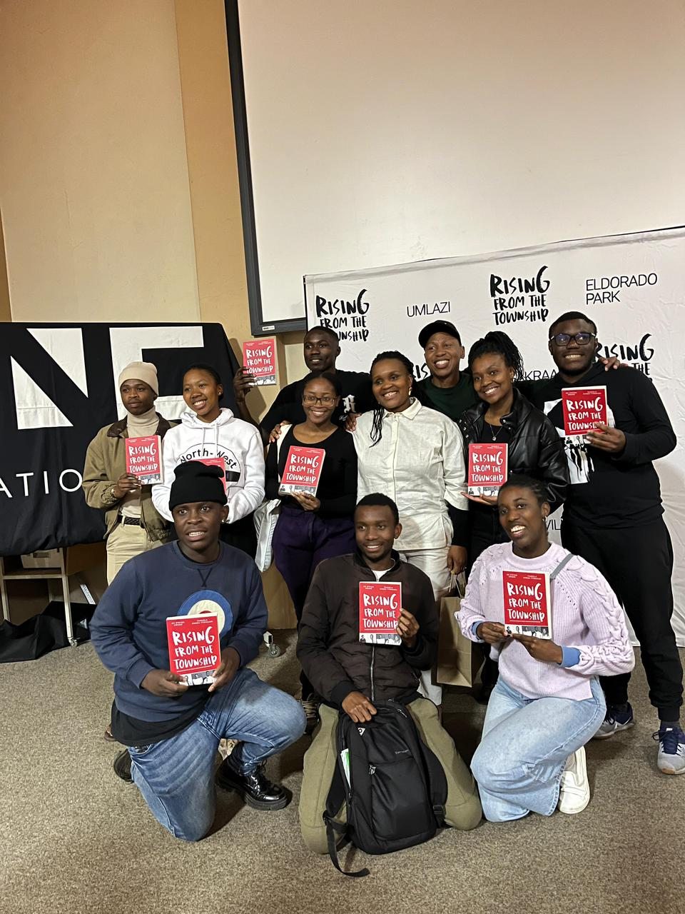 People holding Rising from the Township books during an outreach.
